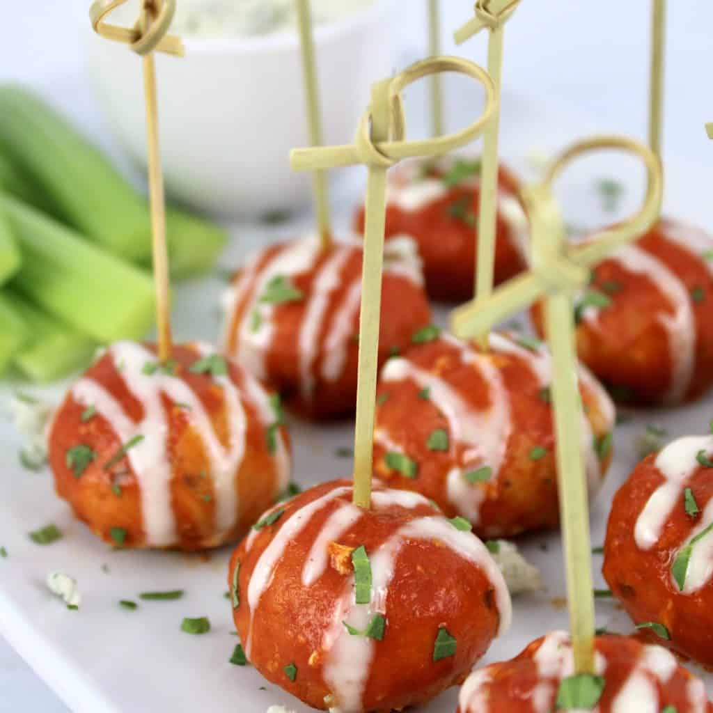 Keto Buffalo Chicken Meatballs on white platter with fancy toothpicks