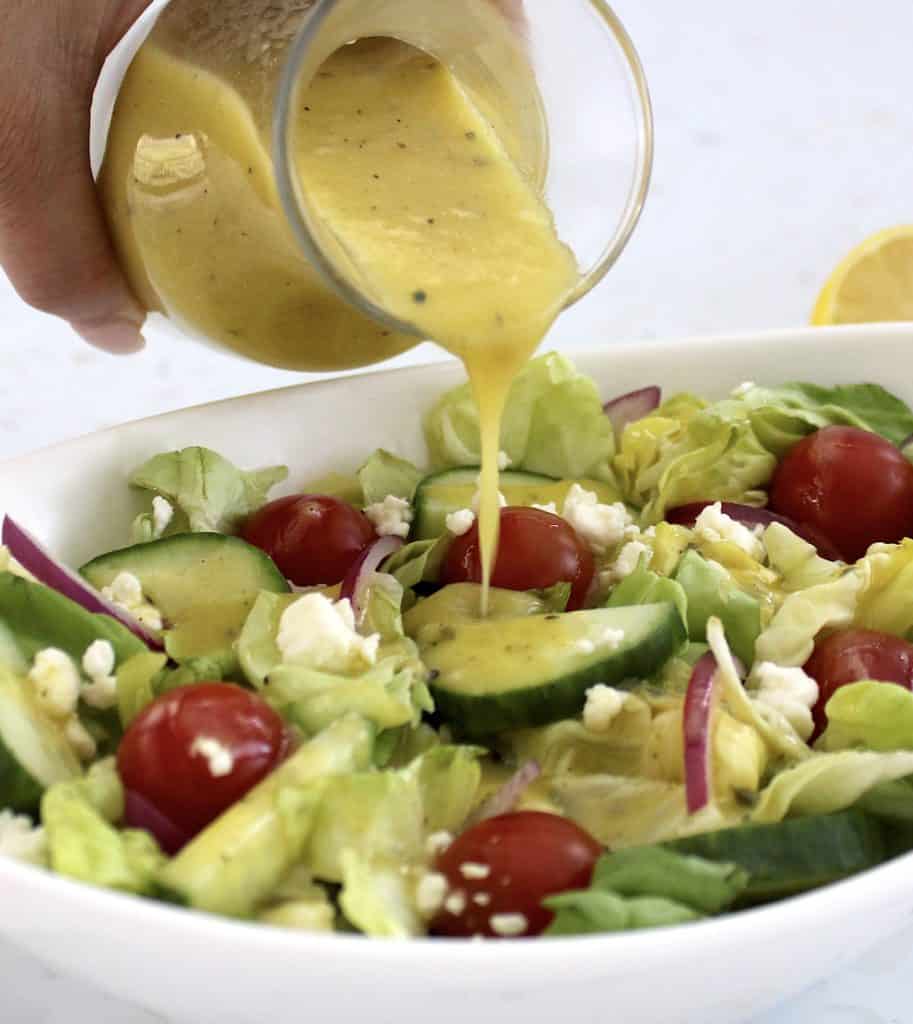 Lemon Vinaigrette in glass jar being poured over salad