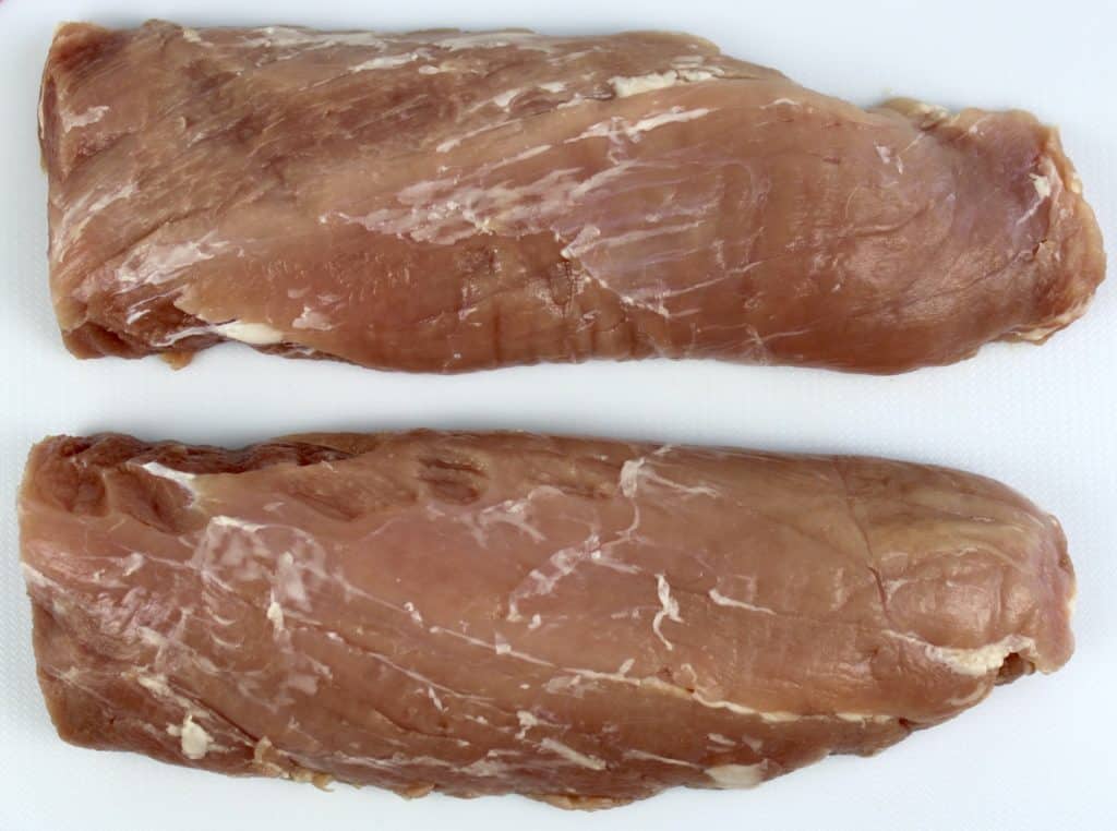 2 pork tenderloins on white cutting board
