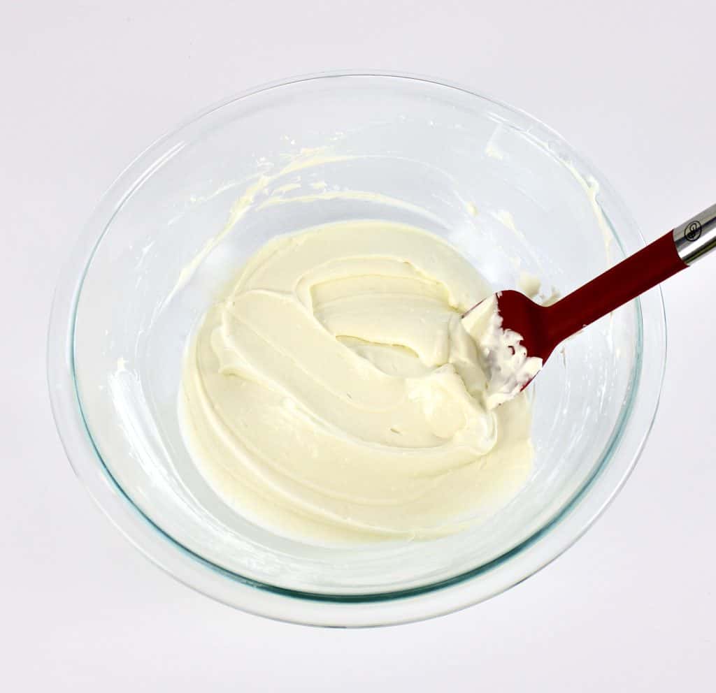 cheesecake mixture in glass bowl with red spoon