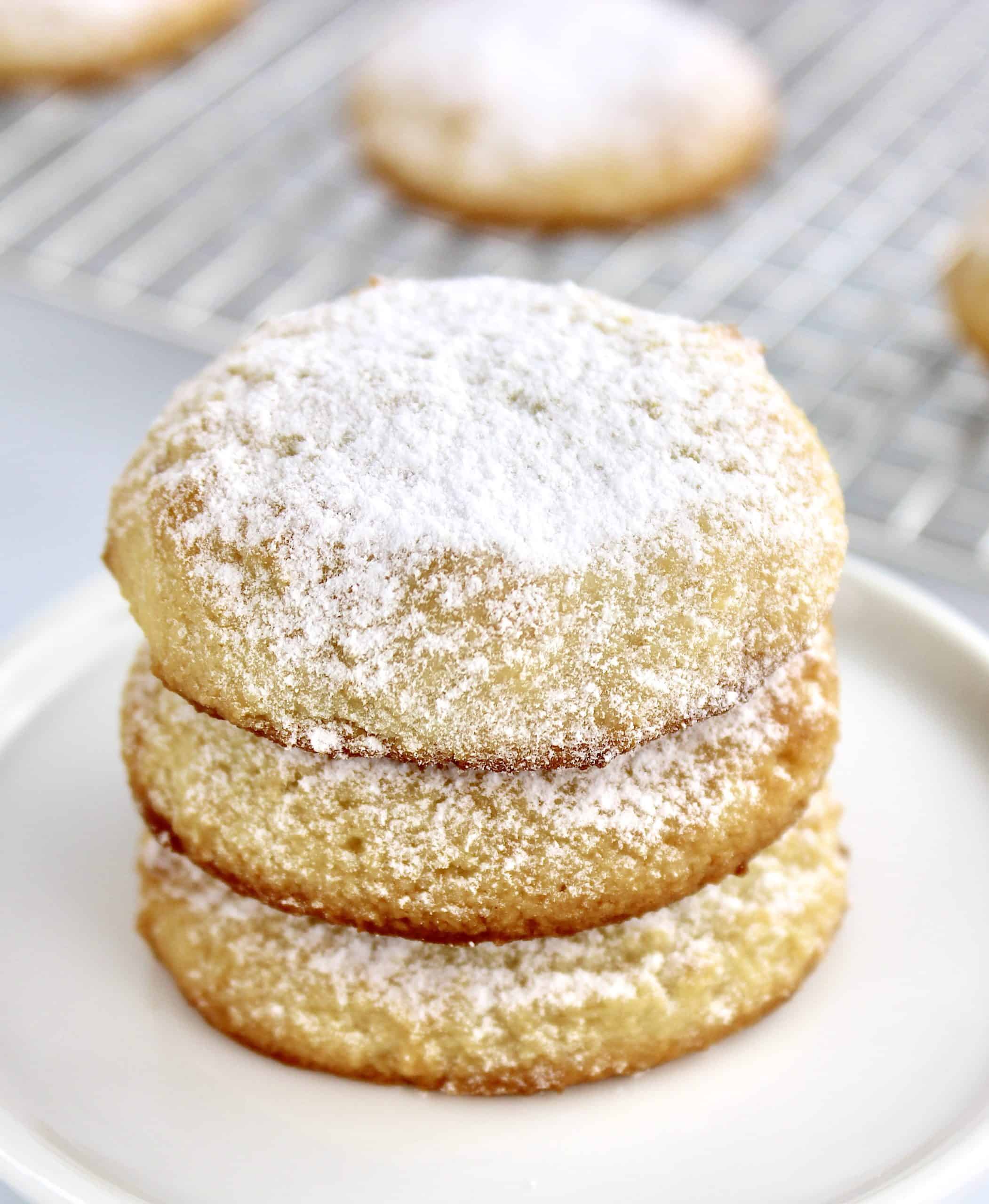 3 cream cheese cookies on white plate with powdered sugar on top